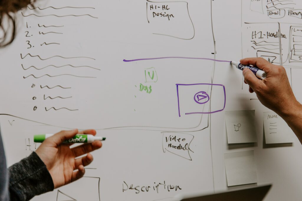 Two hands hover over a whiteboard full of diagrams