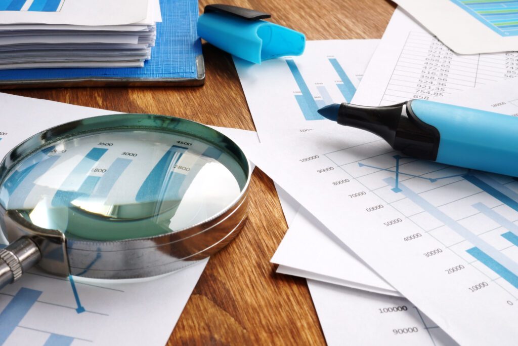 A magnifying glass and a blue highlighter resting on a stack of documents