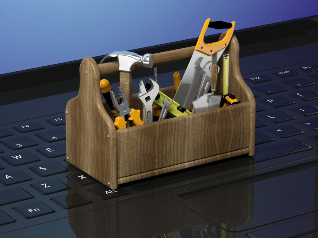 A miniature CGI toolbox with a hammer, saw, wrench, etc, on a laptop keypad