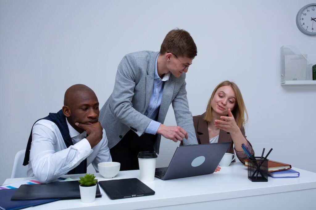 Three people sitting at a desk in front a laptop